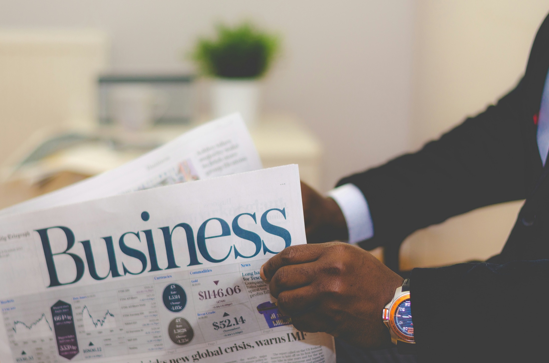 Business başlıklı gazete okuyan iş insanı